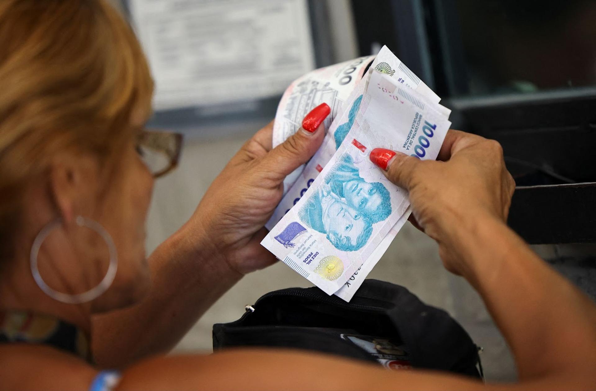 A person holding peso bills. 