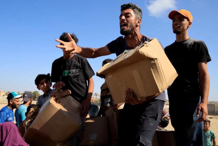 A person carries a box as Palestinians gather near an aid distribution site