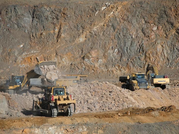 Wheel loaders fill trucks with ore at rare earth mine