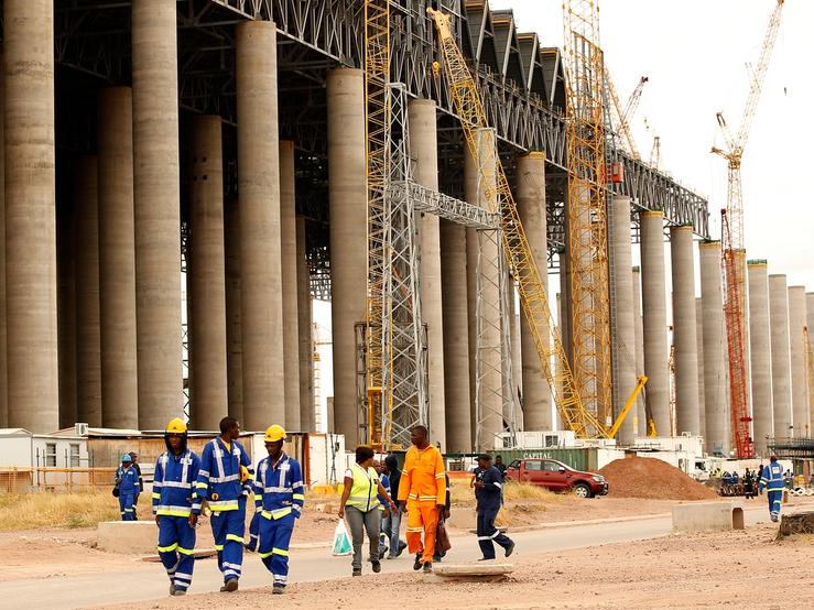 Workers walk past the construction site of a power station.
