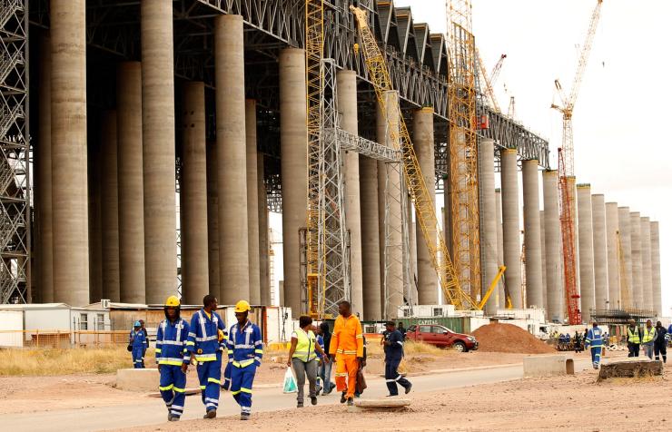 Workers walk past the construction site of a power station.