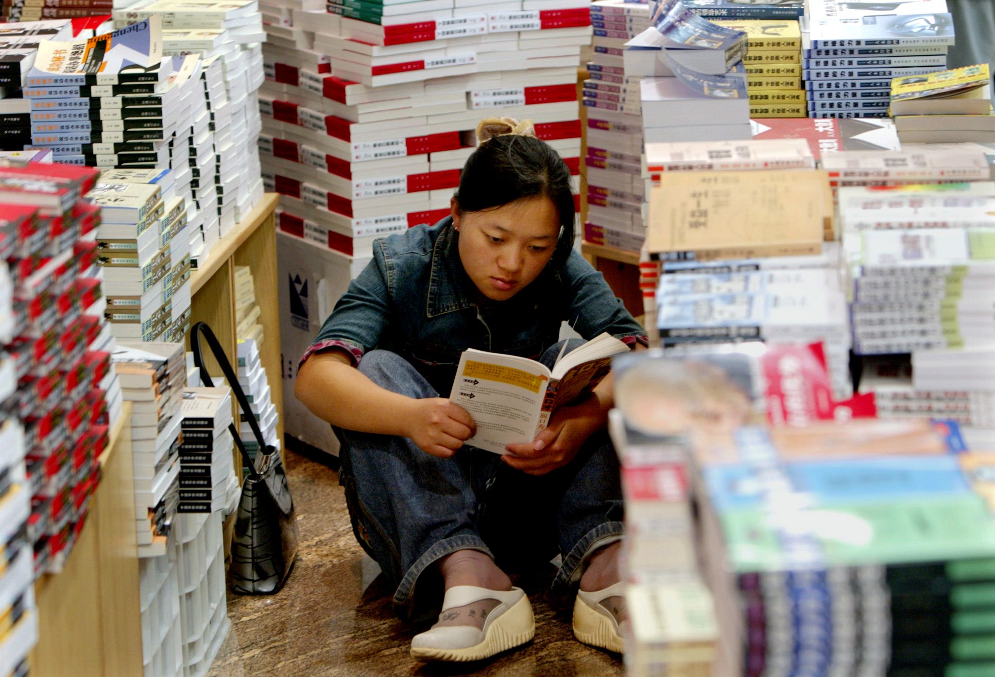 A young woman reading in a bookstore in Beijing, China.