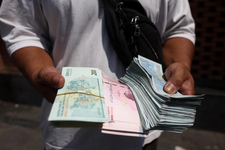 Currency dealer holds stacks of Iranian Rials