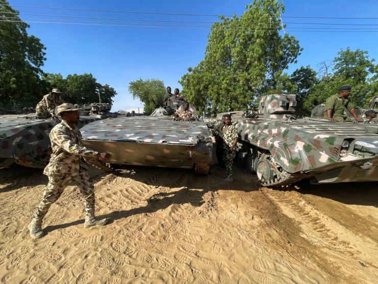 A Nigerian soldier walks past military tanks prepared for deployment.