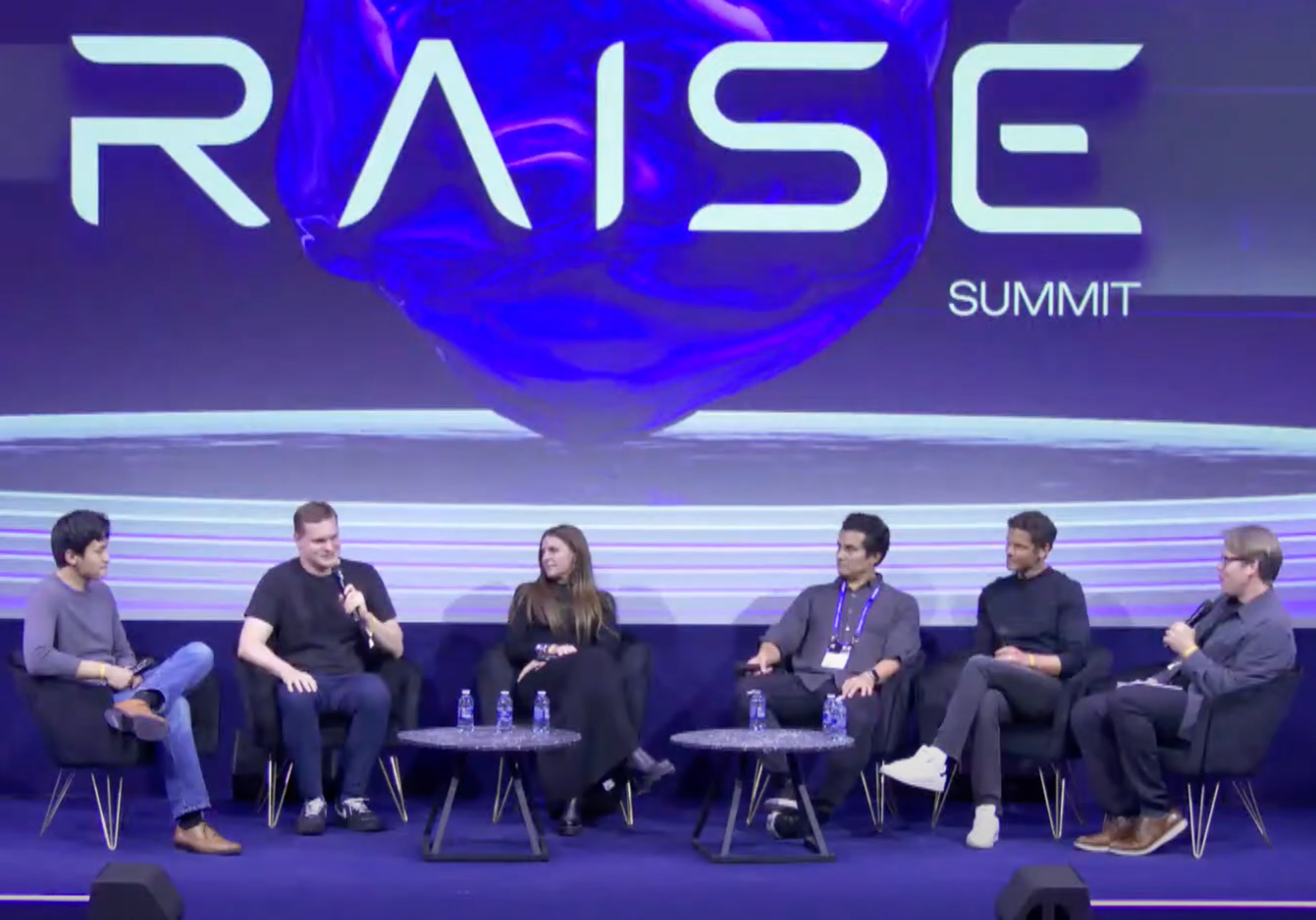 Five RAISE panelists sit on stage with Semafor’s Reed Albergotti