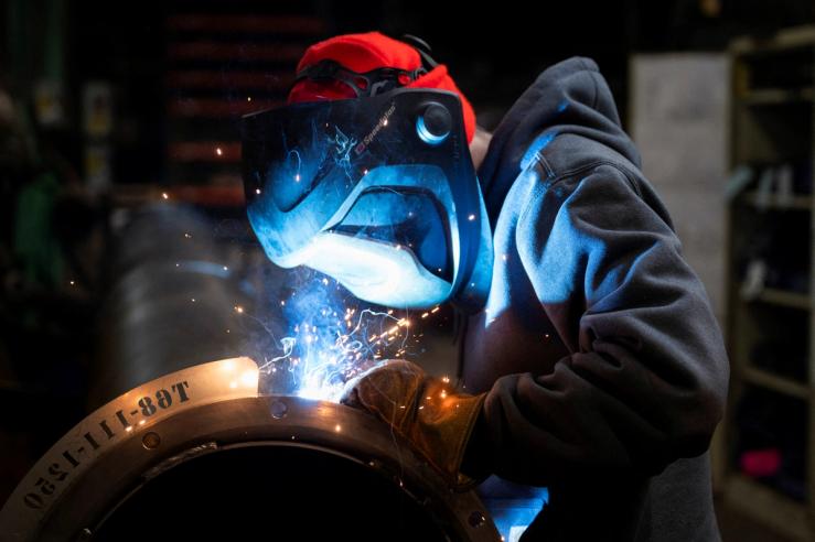 A worker welds a steel tube at HCC, a company that uses parts to make combines, at the factory in Mendota, Illinois.