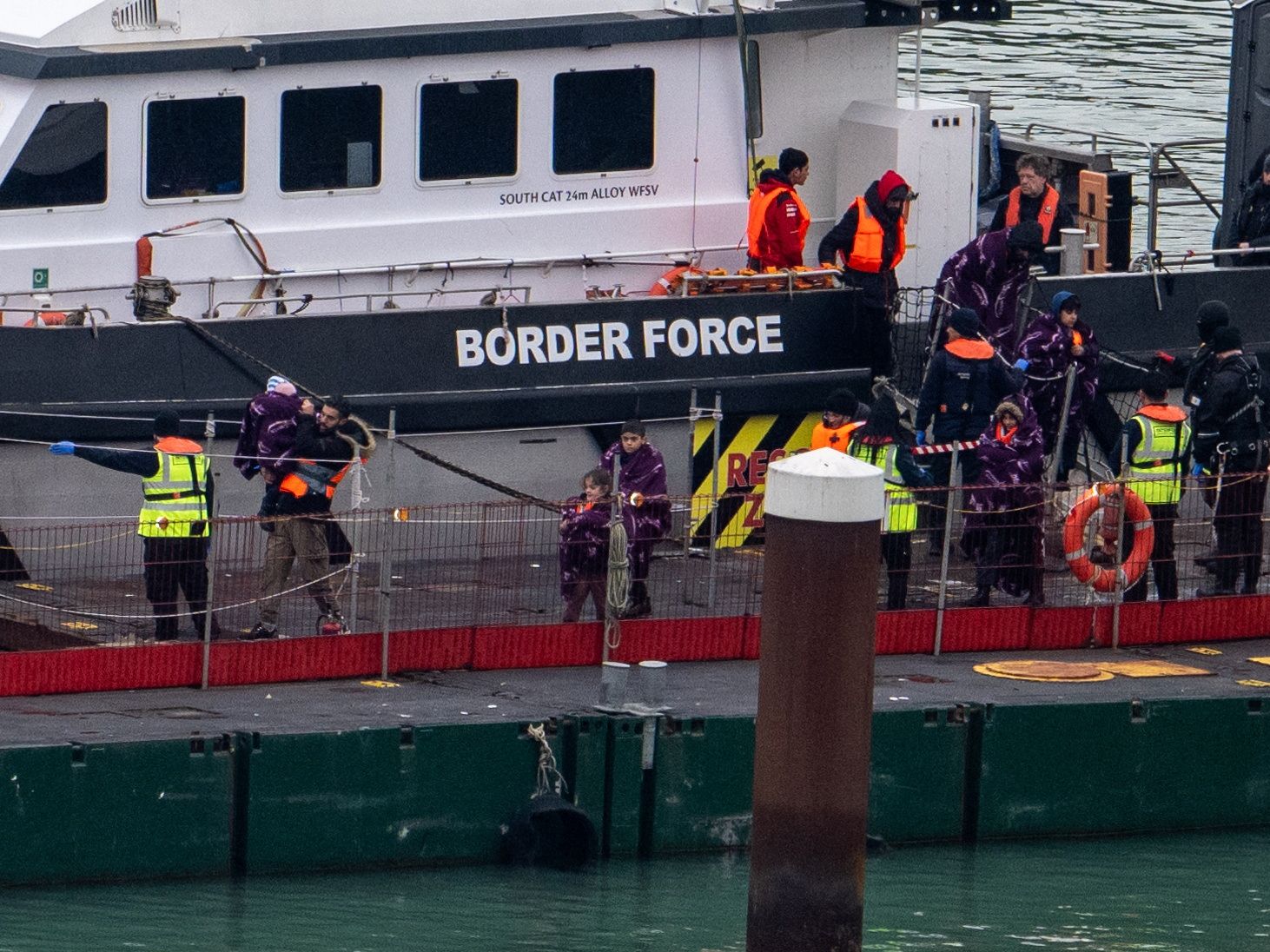 People, believed to be migrants, disembark from a British Border Force vessel as they arrive at the Port of Dover.
