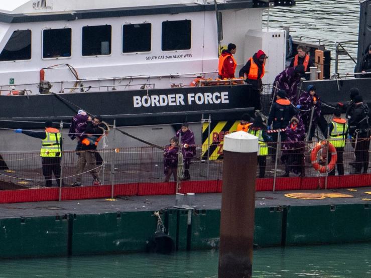People, believed to be migrants, disembark from a British Border Force vessel as they arrive at the Port of Dover.