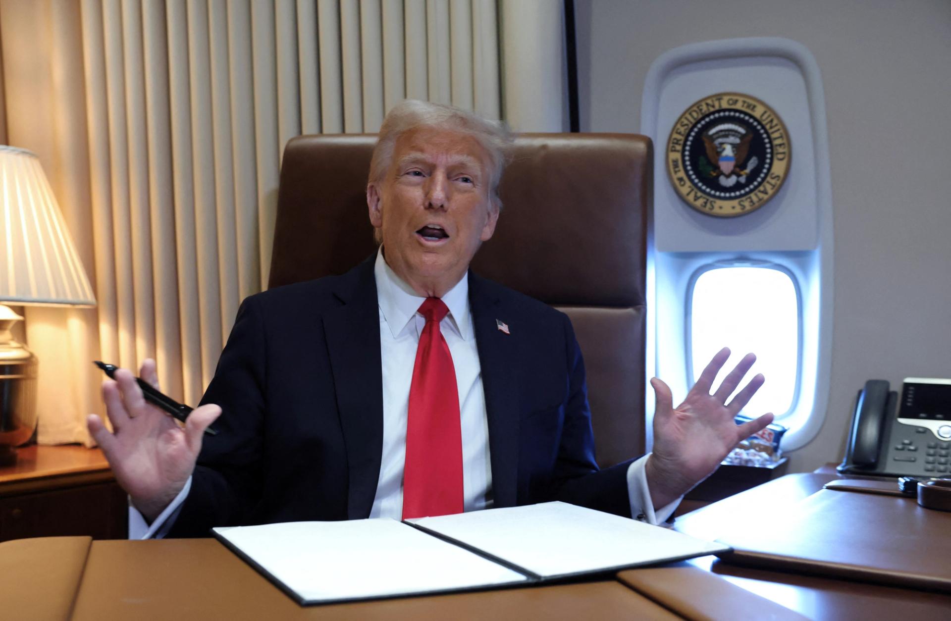 Donald Trump speaks to reporters on board Air Force One