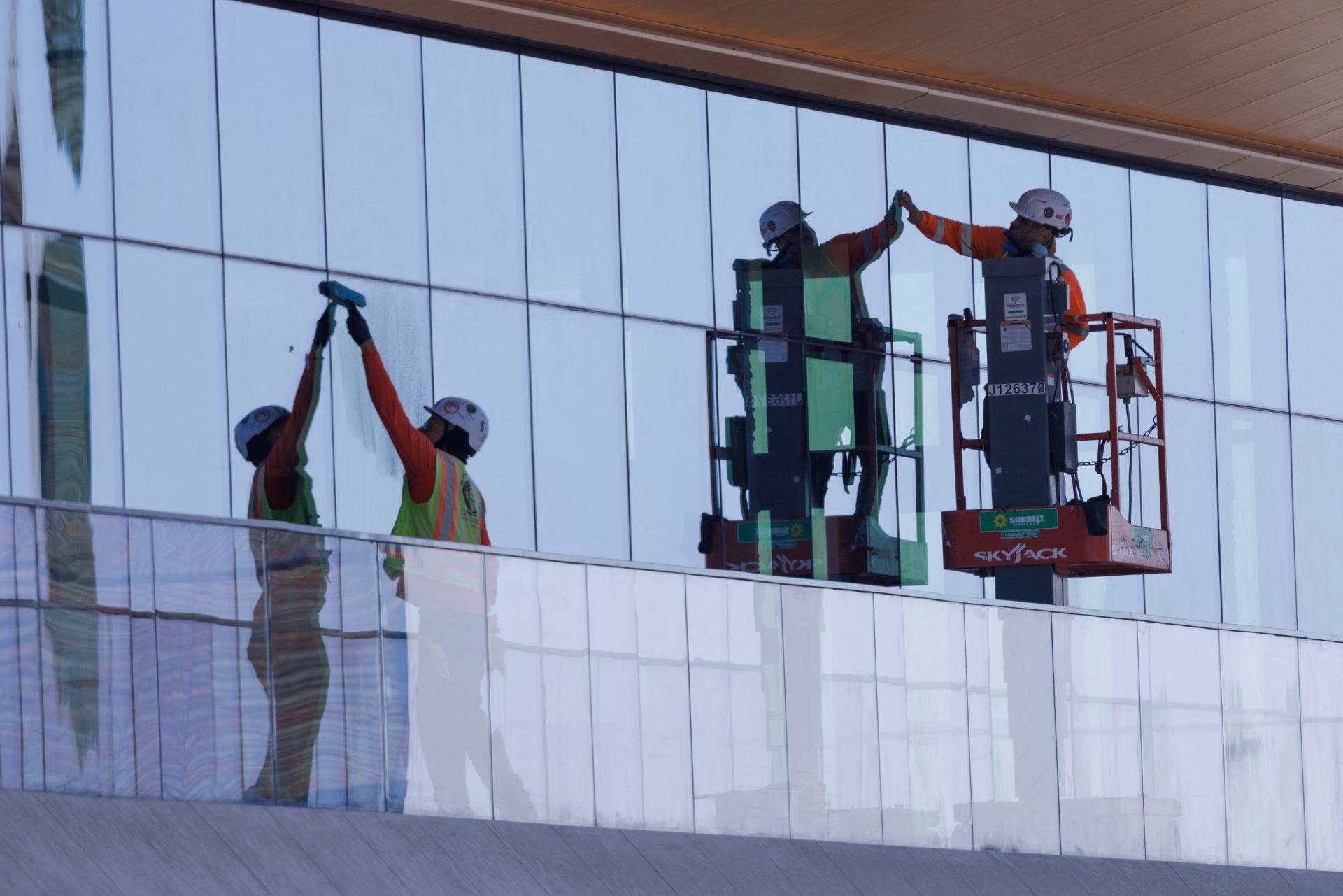 Construction workers install windows on a nearly completed office building in San Diego