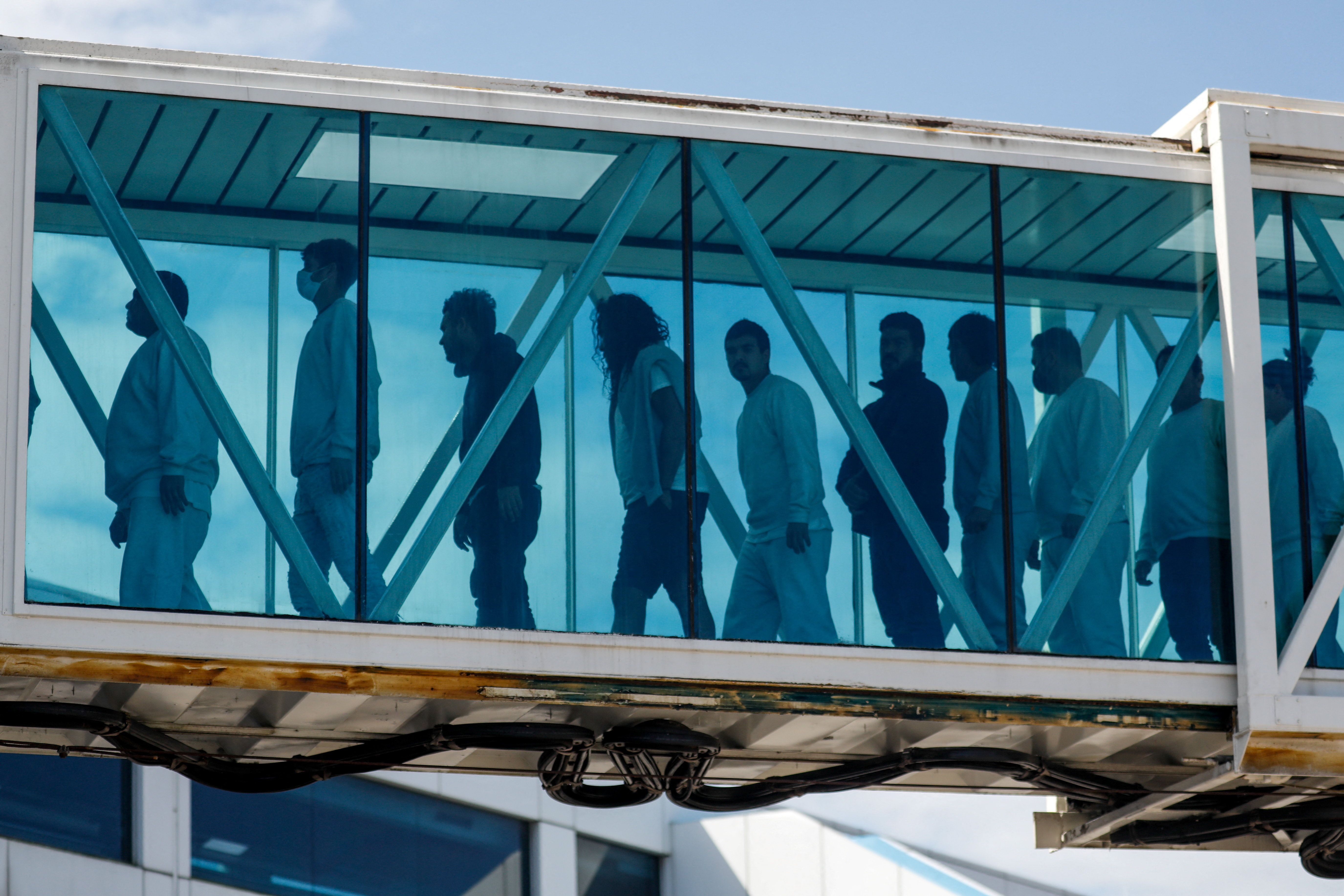 Migrants deported from the US walk a jet bridge. 