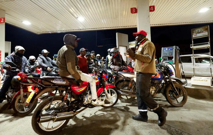 A fuel pump attendant talks to motorcycle taxi riders waiting to refuel their motorcycles at a TotalEnergies petrol station in Nairobi.