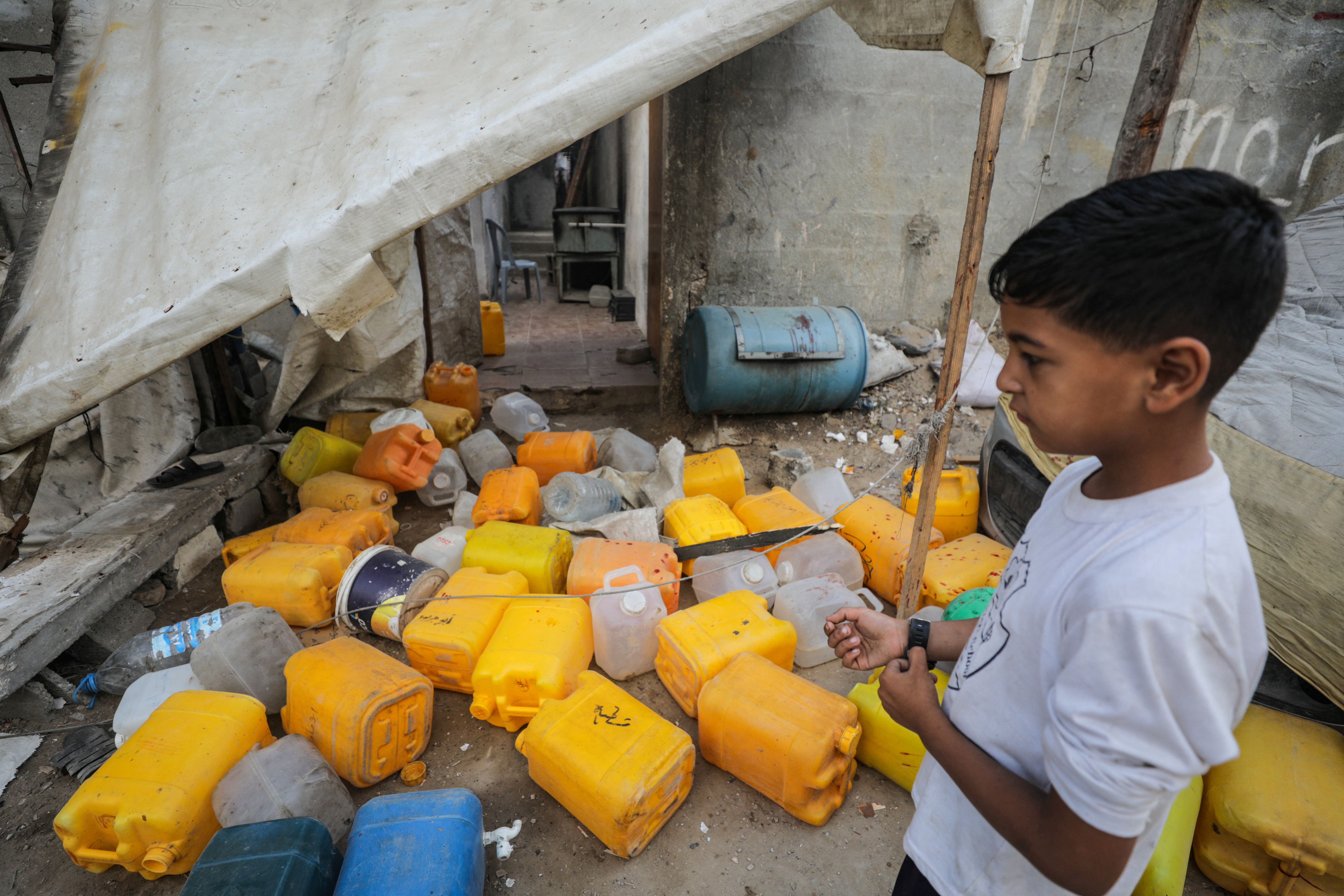 A Palestinian boy inspects the site of an Israeli strike that killed Palestinians, gathered to collect water from a distribution point, according to medics, in Nuseirat in the central Gaza Strip July 13, 2025. 