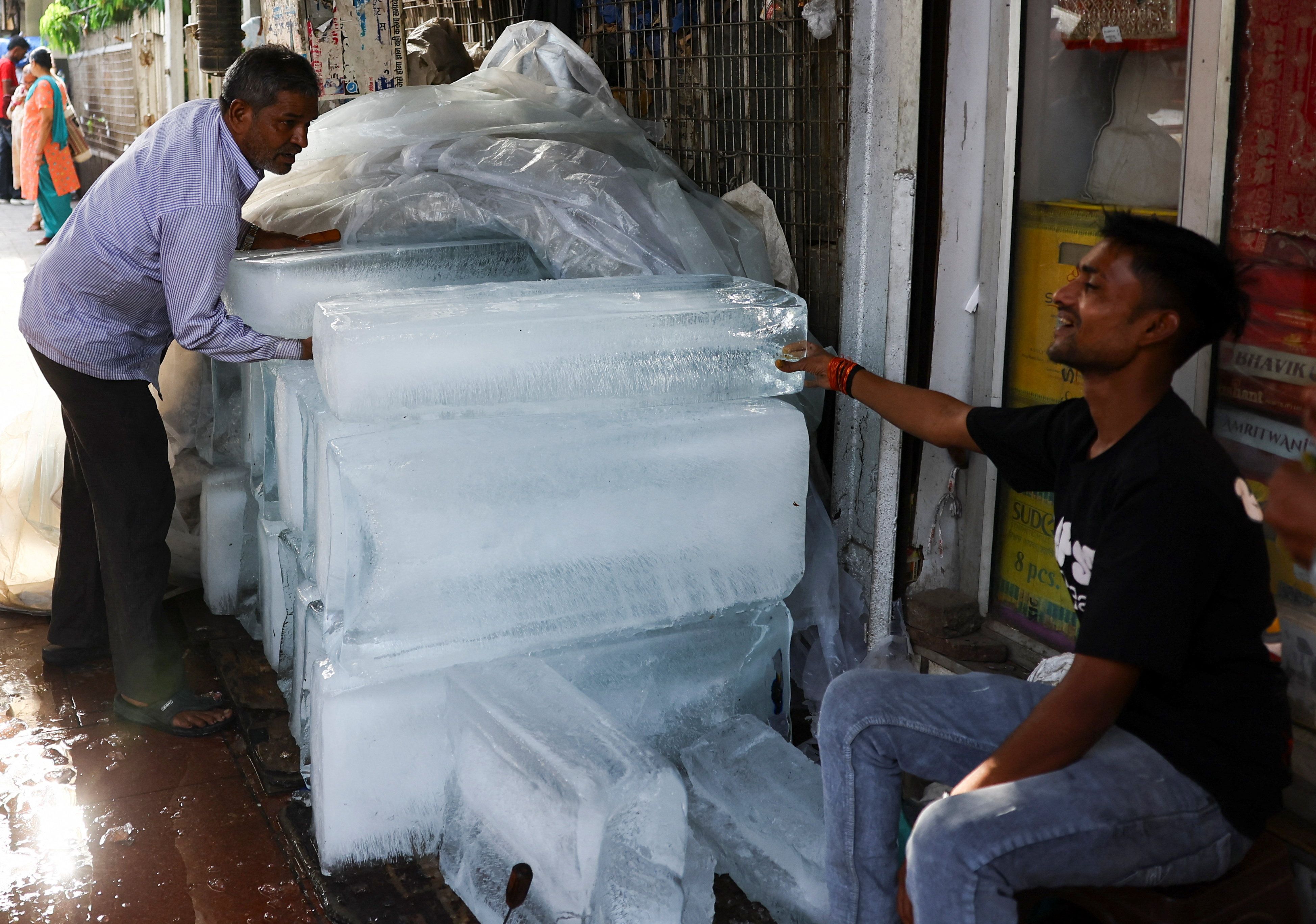  man moves blocks of ice for sale in a market on a hot summer day.