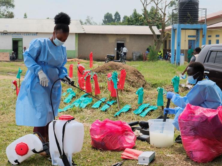 Medical workers dressed in personal protective equipment (PPE) disinfect their equipment at an Ebola treatment centre.