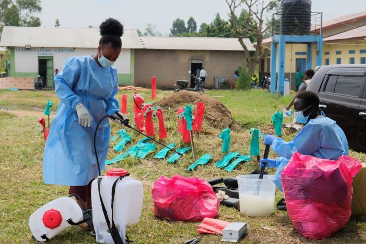 Medical workers dressed in personal protective equipment (PPE) disinfect their equipment at an Ebola treatment centre.