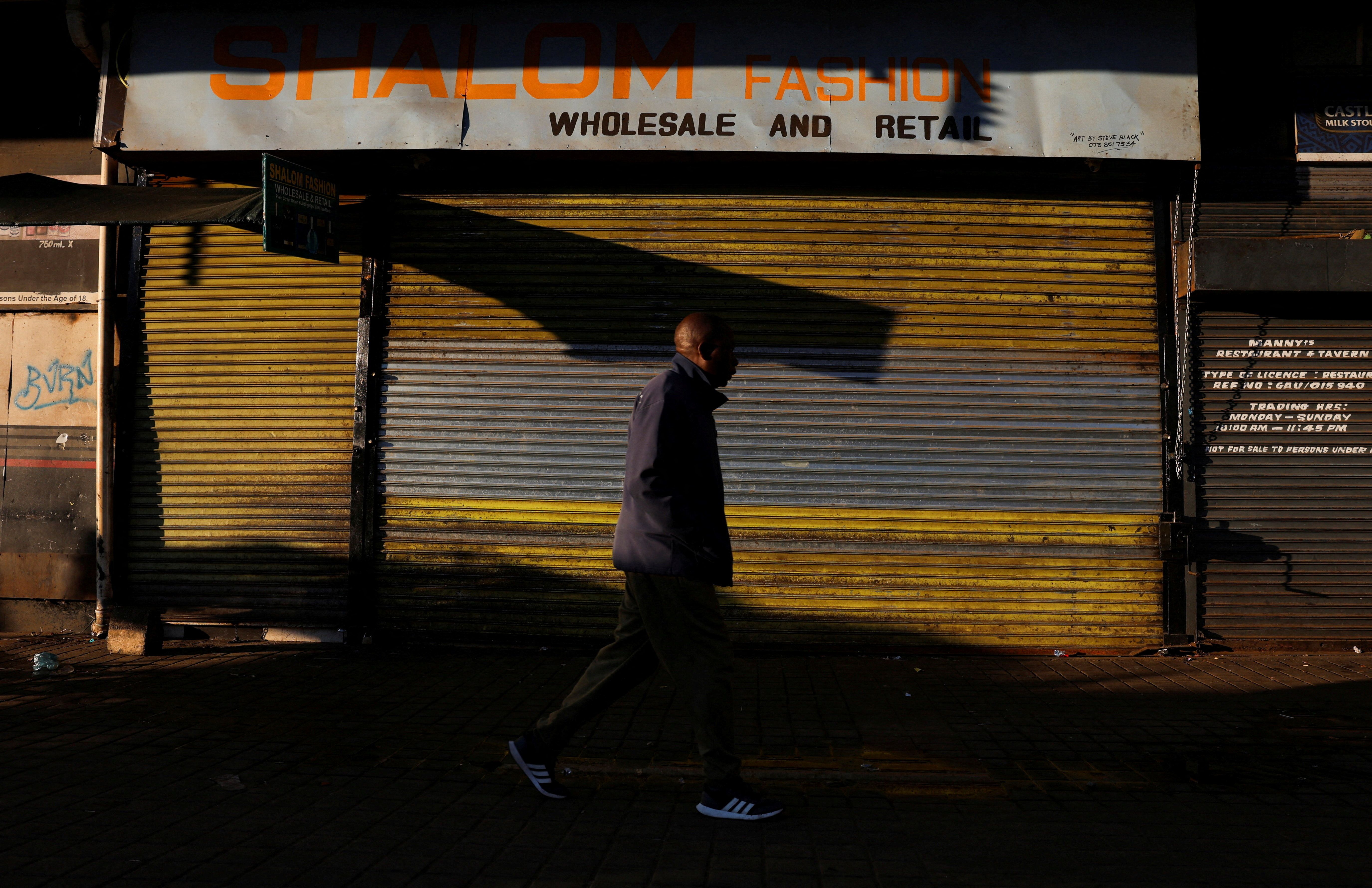 A man walks by a closed shop in Johannesburg.