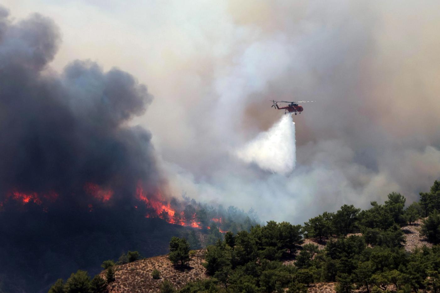 A firefighting helicopter makes a water drop as a wildfire burns near the village of Archangelos, on the island of Rhodes, Greece, July 24, 2023. REUTERS/Nicolas Economou