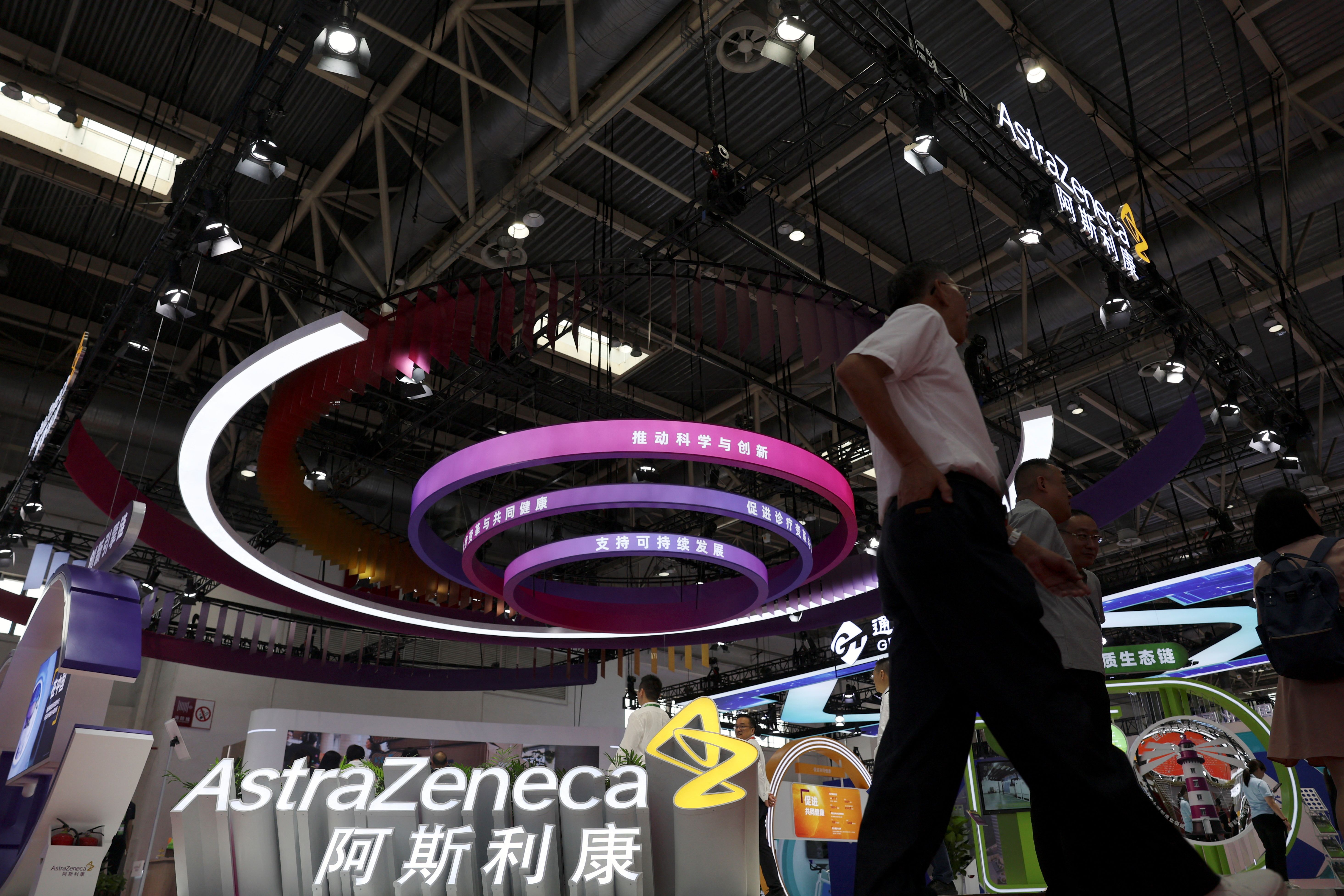 People walk past the AstraZeneca booth during the China International Supply Chain Expo in Beijing