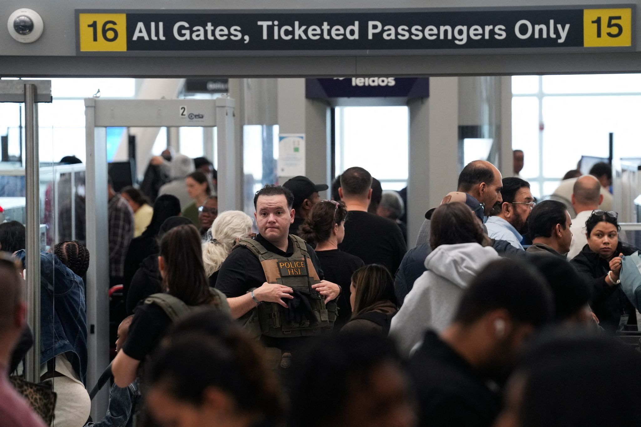 An Immigration and Customs Enforcement agent stands at a TSA checkpoint