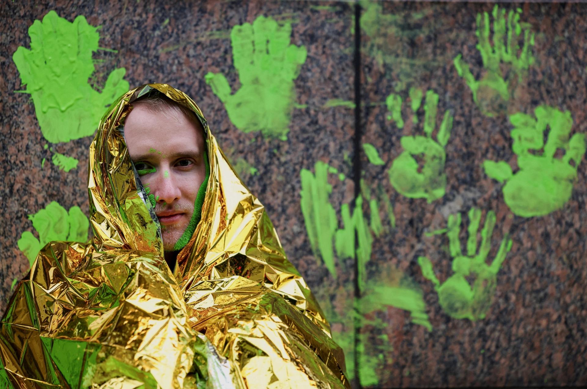 A climate activist sits in front of a wall outside the venue for the World LNG Summit in Berlin.