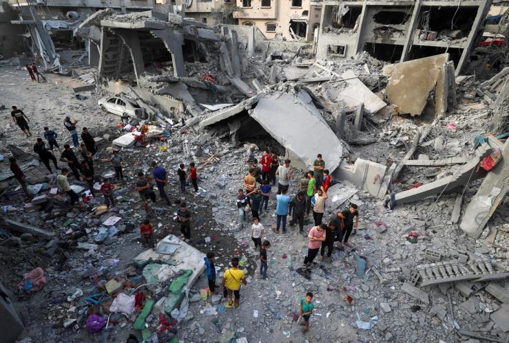 Palestinians inspect the site of an Israeli strike on a house in Gaza.