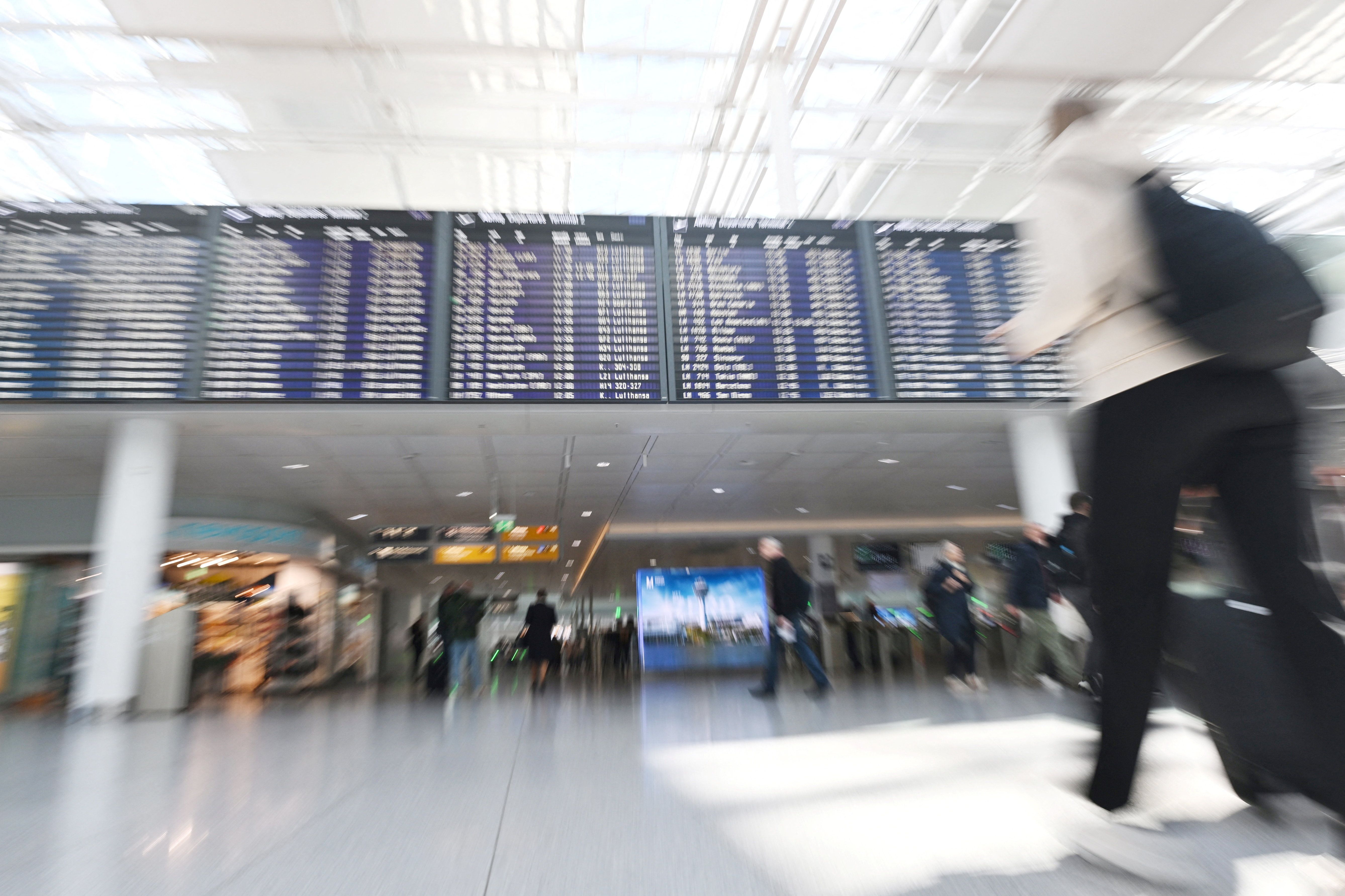 People walk a near display board at the airport in Munich, Germany.