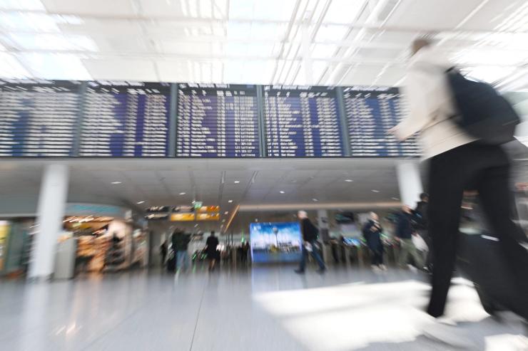 People walk a near display board at the airport in Munich, Germany.