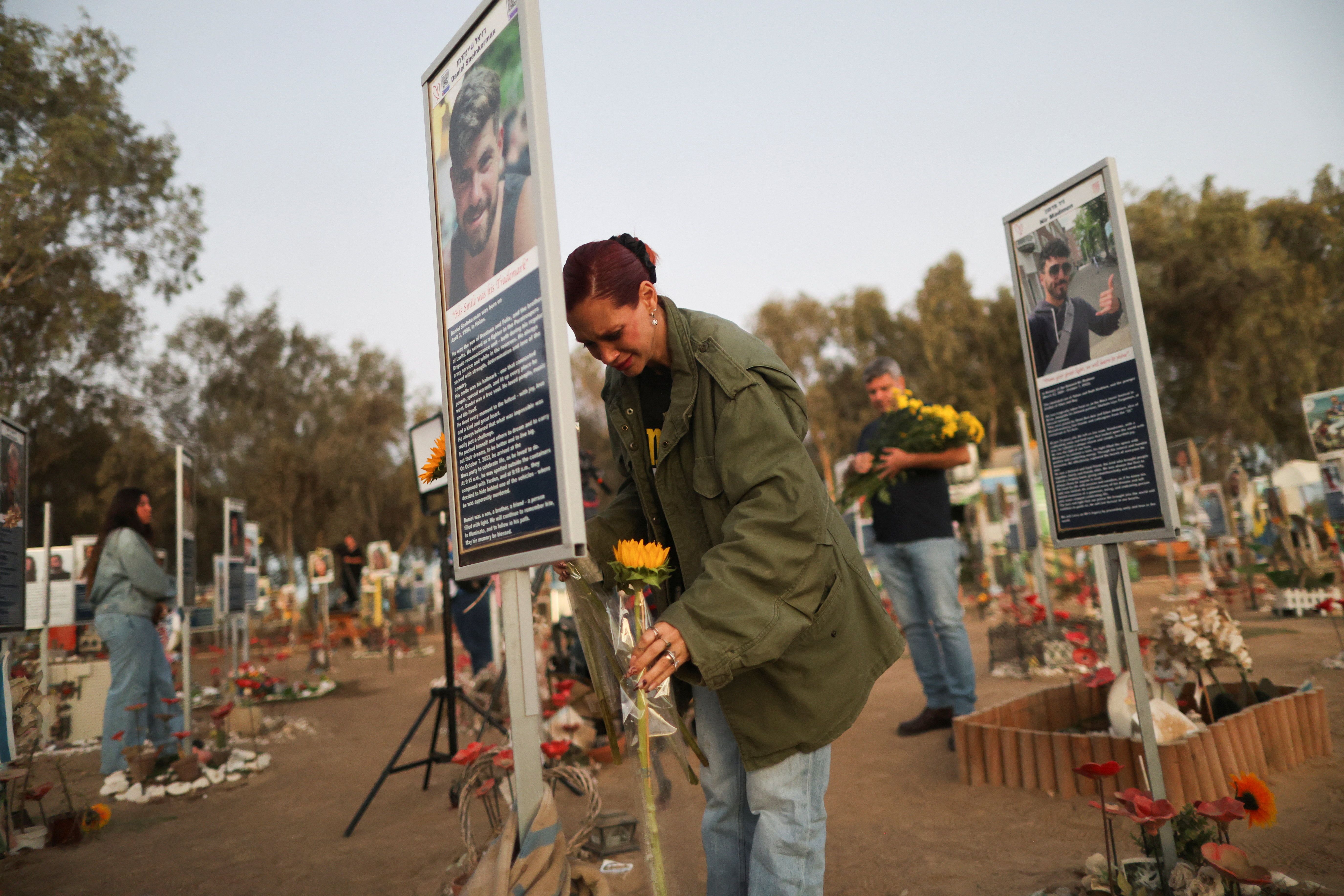 A woman places a flower as people grieve at the site of the Nova festival where partygoers were killed and kidnapped.