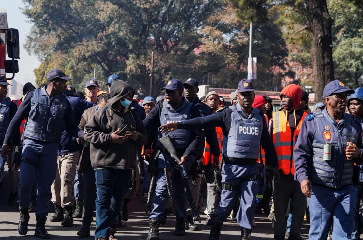 Police officers gesture towards a suspected rioter amidst the eviction of residents from an apartment complex.