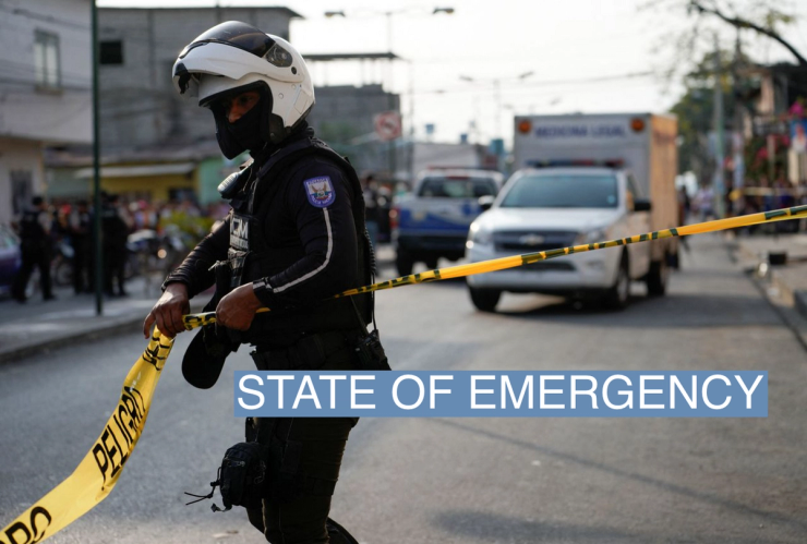 A police officer puts up a police tape at a crime scene where colleagues were killed in response to prisoner transfers from overcrowded prisons, prompting President Guillermo Lasso to declare a state of emergency in two provinces, in Guayaquil, Ecuador