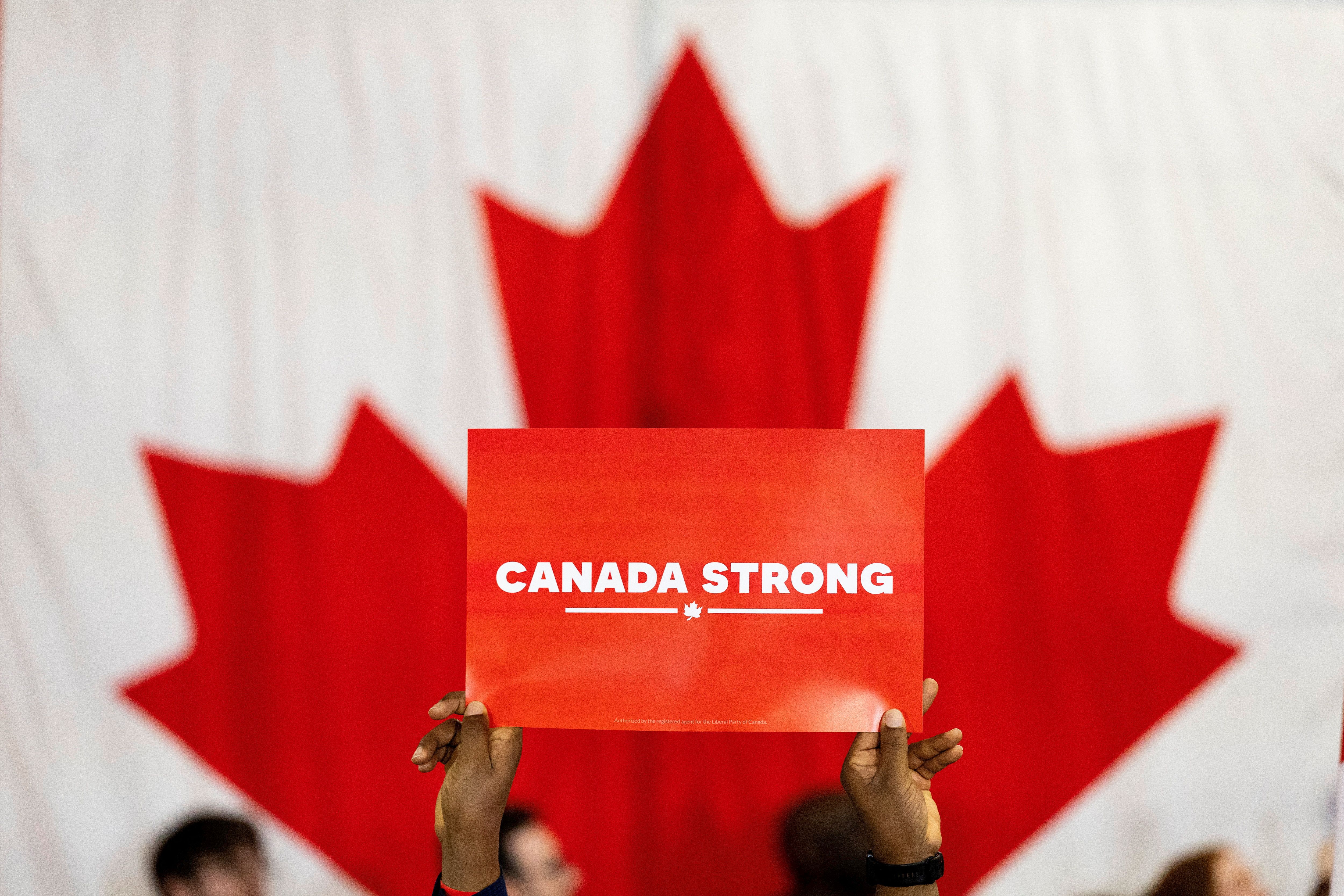 A supporter holds a sign as Canada’s Prime Minister Mark Carney delivers a speech.