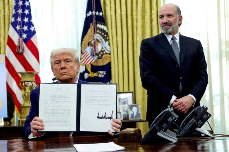 U.S. President Donald Trump holds an executive order about tariffs increase, flanked by U.S. Commerce Secretary Howard Lutnick, in the Oval Office of the White House in Washington, D.C.