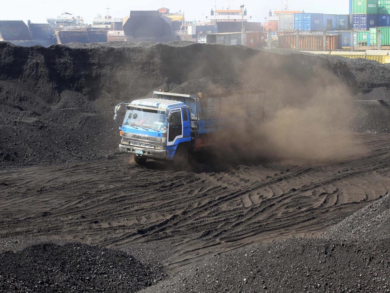 worker drives an open truck full of coal.