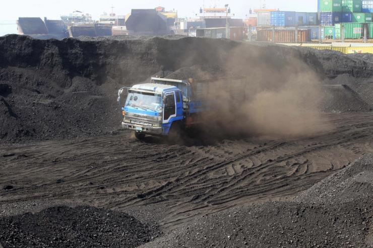 worker drives an open truck full of coal.