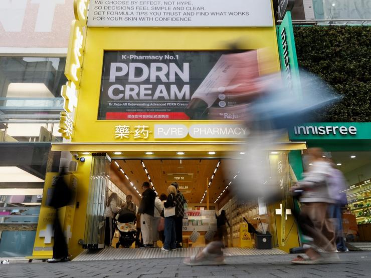 Tourists walk past a cosmetics store at Myeongdong shopping district in Seoul, South Korea.