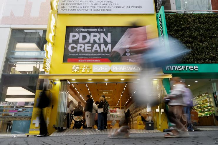 Tourists walk past a cosmetics store at Myeongdong shopping district in Seoul, South Korea.