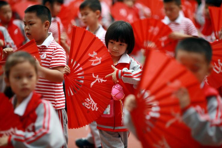Children perform a Kung Fu Fan dance while carrying plastic eggs during the “egg protection” activity designed by the school for its students to understand motherhood in Guilin, Guangxi autonomous region