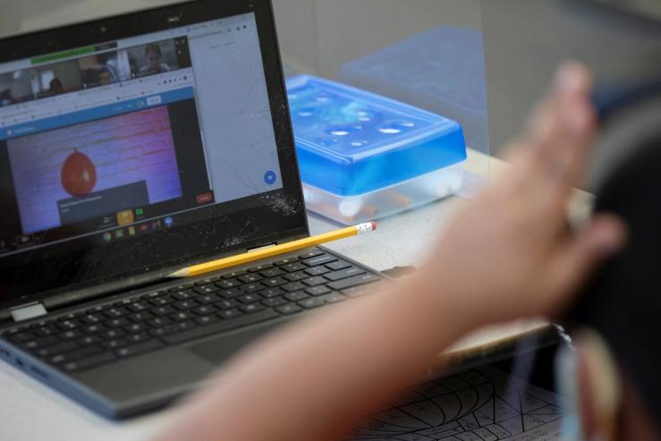A student attends a virtual class on a laptop