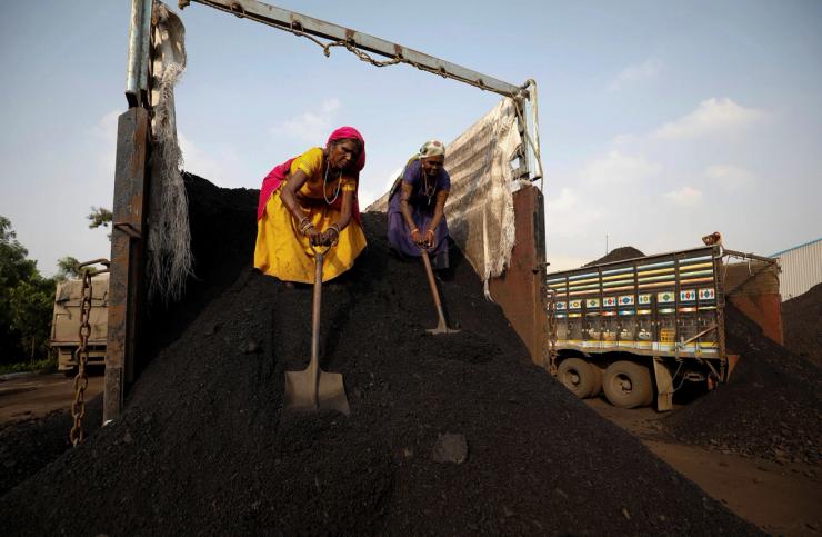 Workers unload coal from a supply truck at a yard on the outskirts of Ahmedabad, India October 12, 2021.