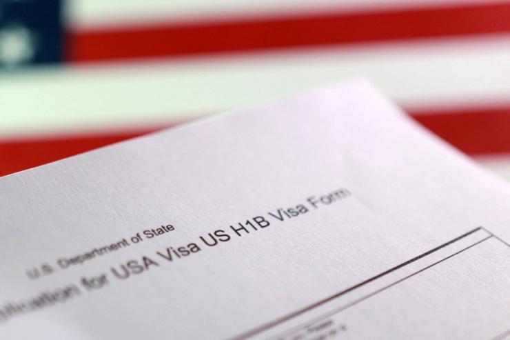 A U.S. flag and a U.S. H-1B Visa application form
