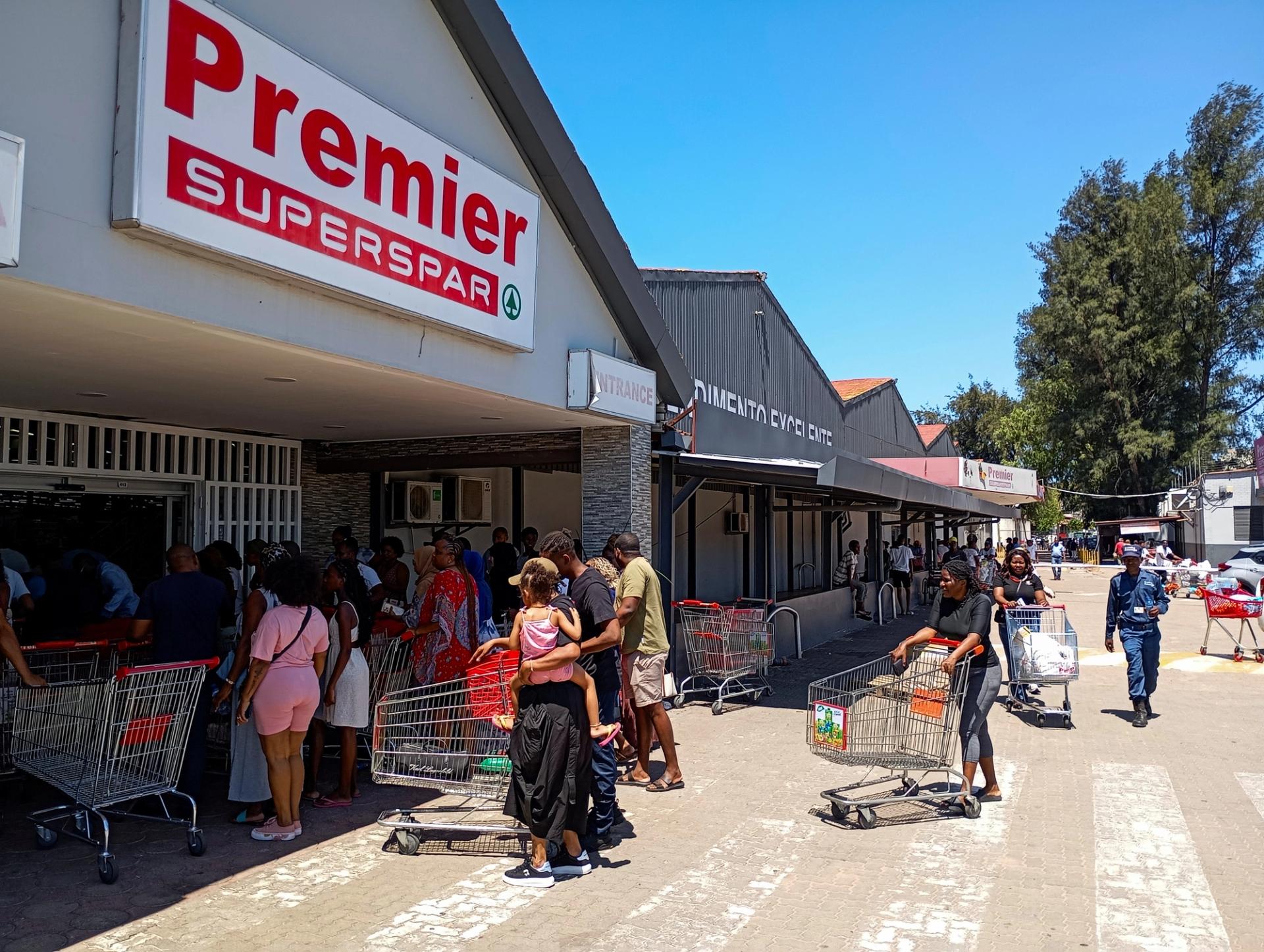 Locals queue at a grocery store in Mozambique.