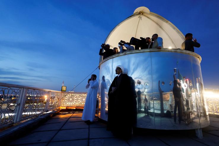 People look through binoculars and a telescope to view the moon ahead of Ramadan to mark the beginning of the holy fasting month, in the holy city of Najaf, Iraq March 22, 2023. REUTERS/Alaa Al-Marjani