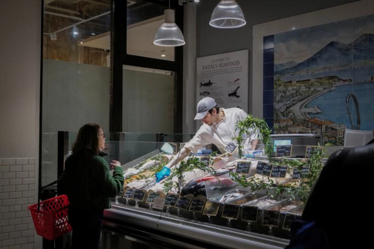 A woman shops a fish at a store in New York City.