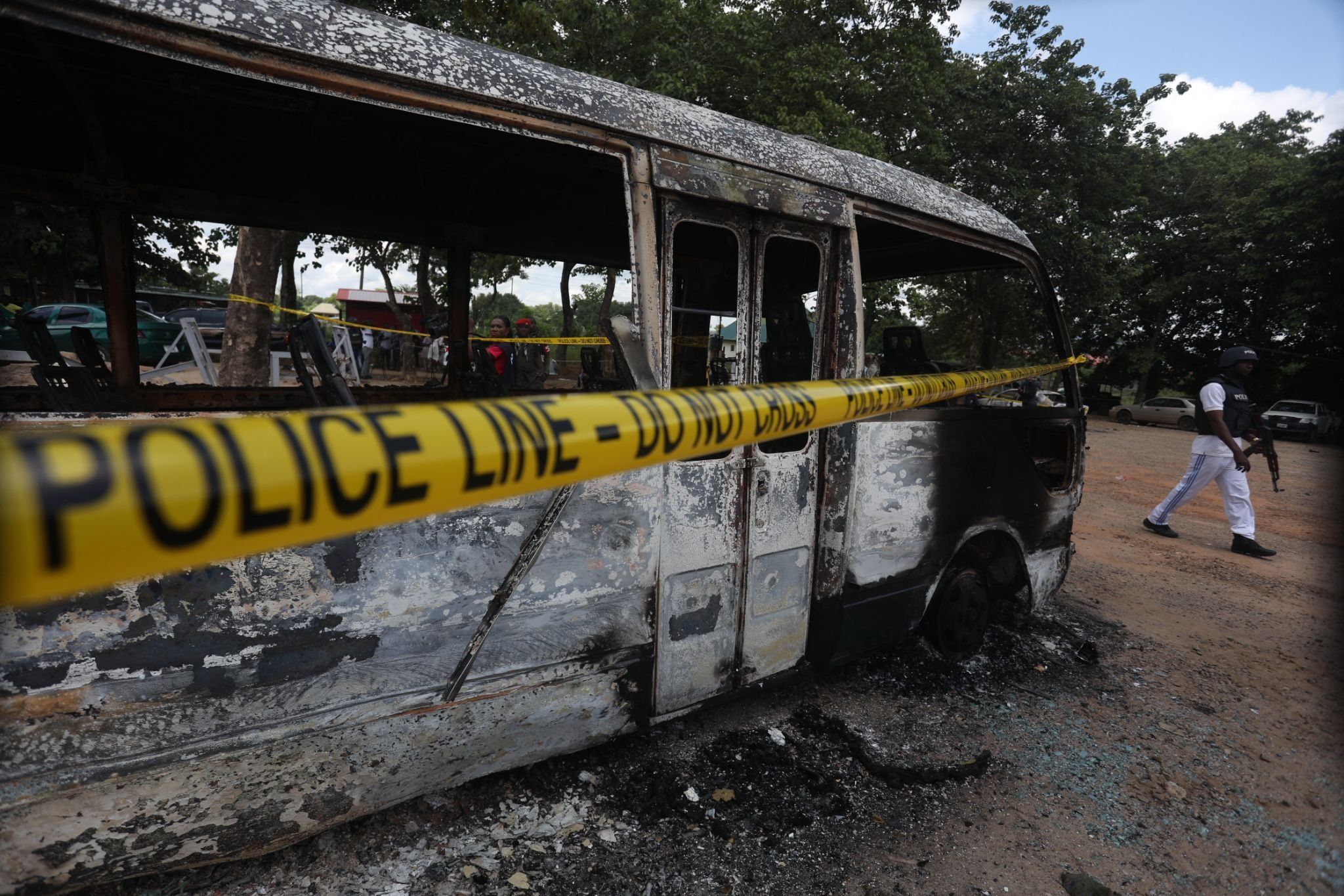 A police officer walks beside a burnt prison vehicle in Abuja, Nigeria on July 6, 2022, after a suspected Boko Haram attack.