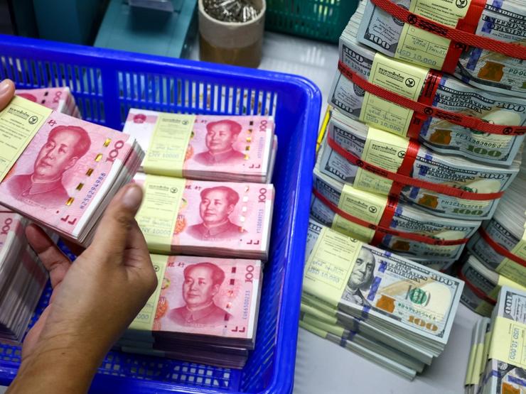 A bank employee count China’s renminbi (RMB) or yuan notes next to U.S. dollar notes at a Kasikornbank in Bangkok