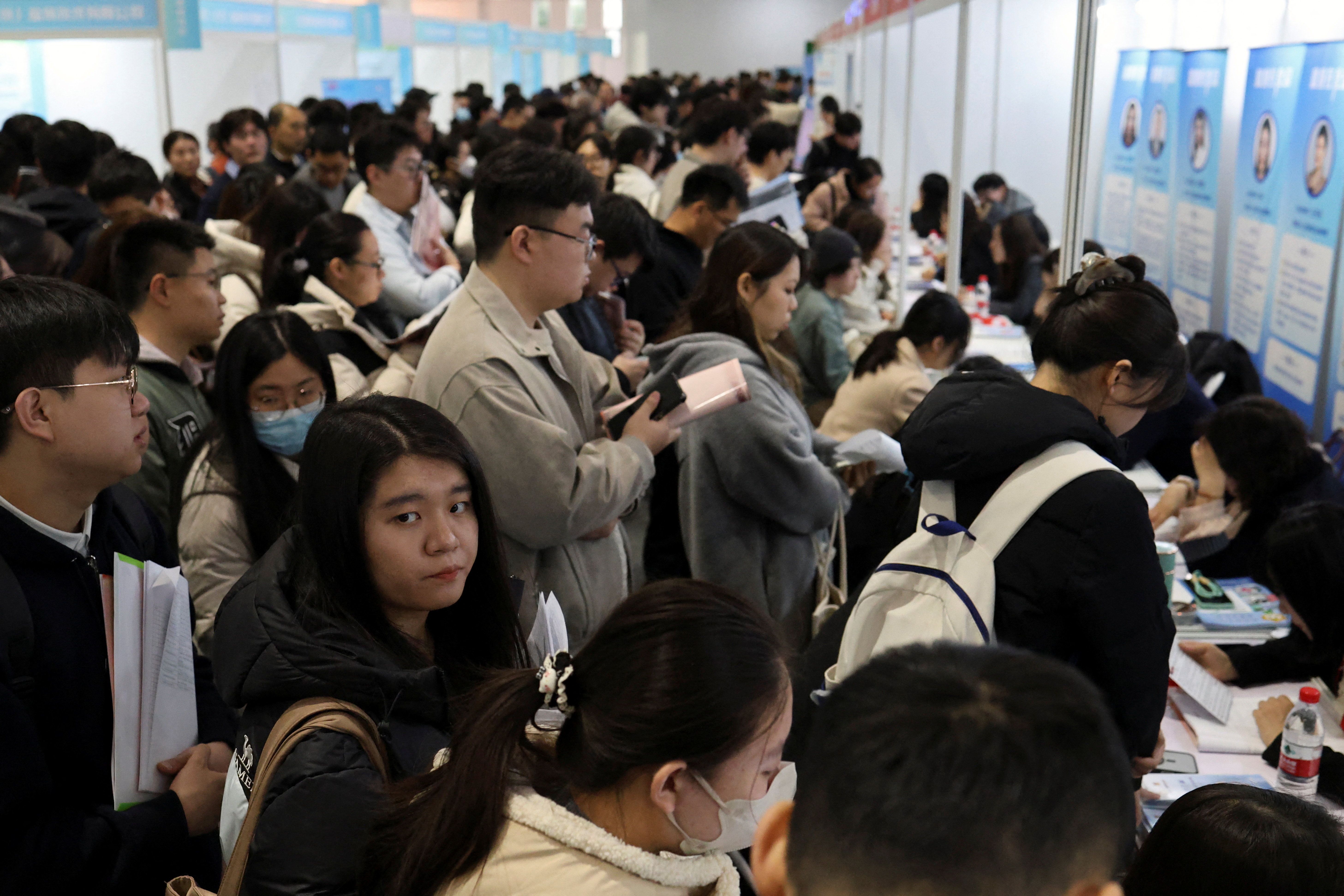 People line up at career guidance booths during a job fair in Beijing.