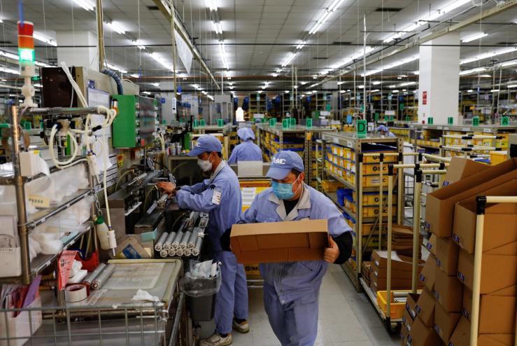 Employees work on a production line manufacturing mechanical parts.