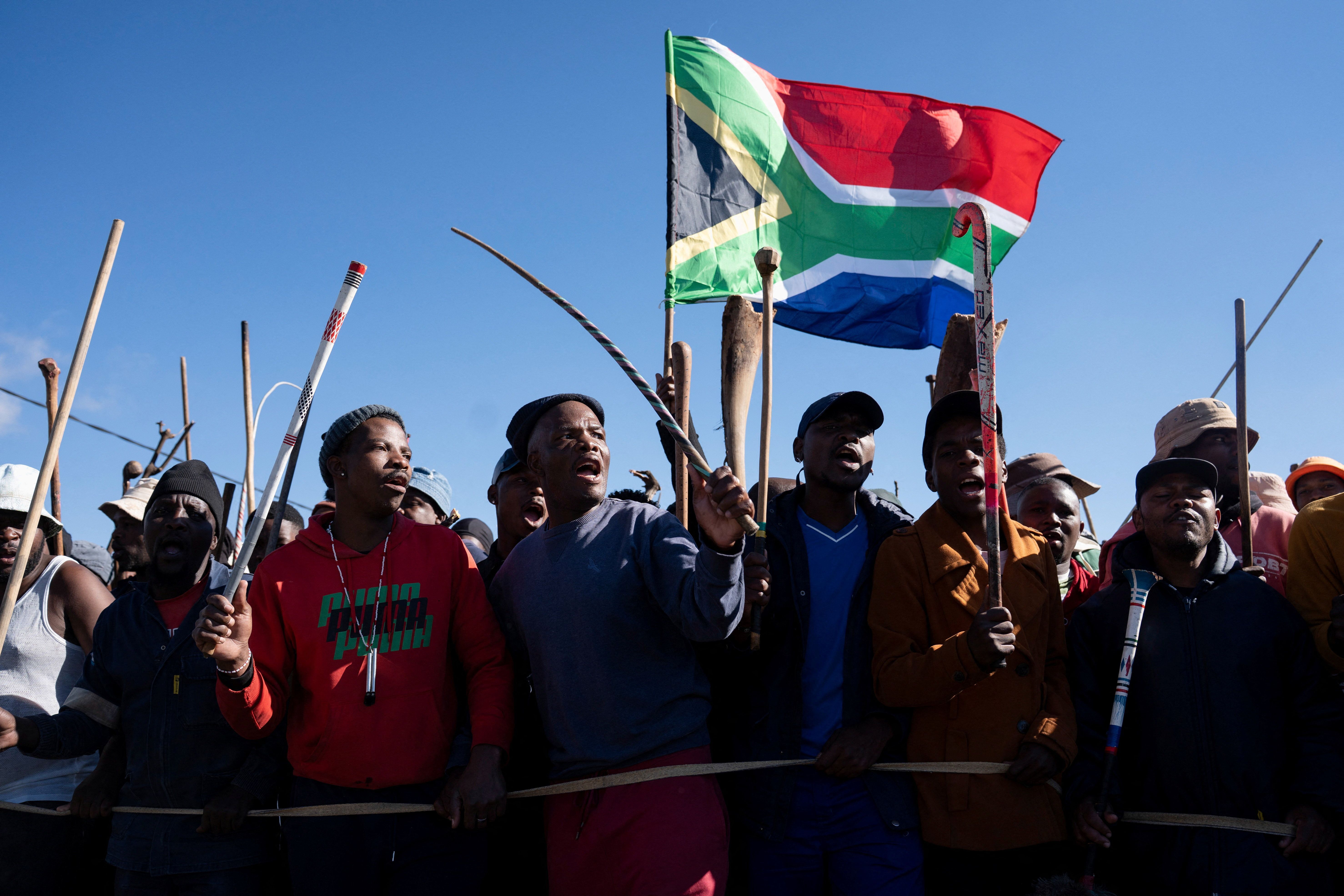 Demonstrators carry sticks and a flag during a protest calling for the deportation of undocumented immigrants.