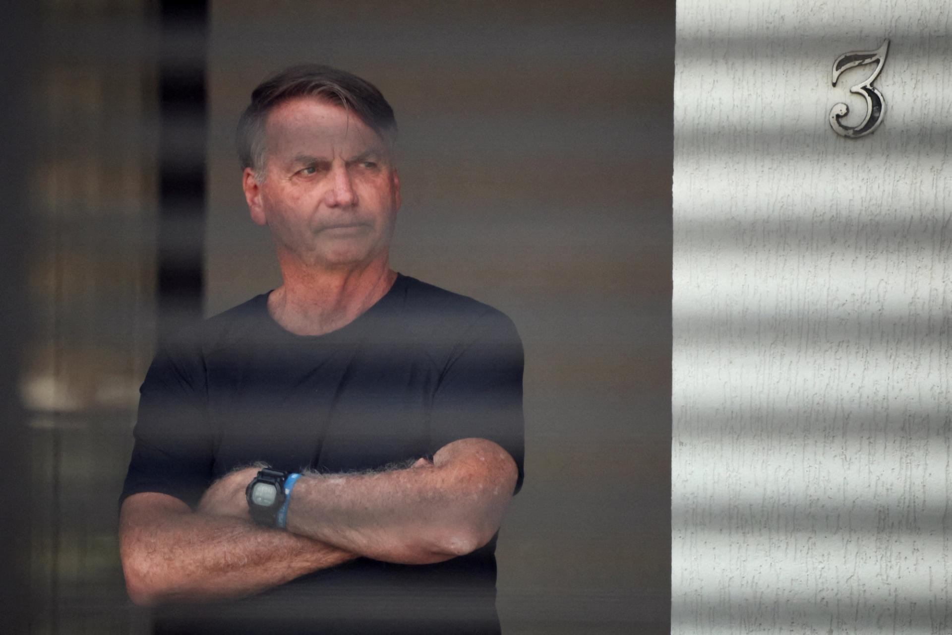 Brazil’s former President Jair Bolsonaro stands at his home while under house arrest.